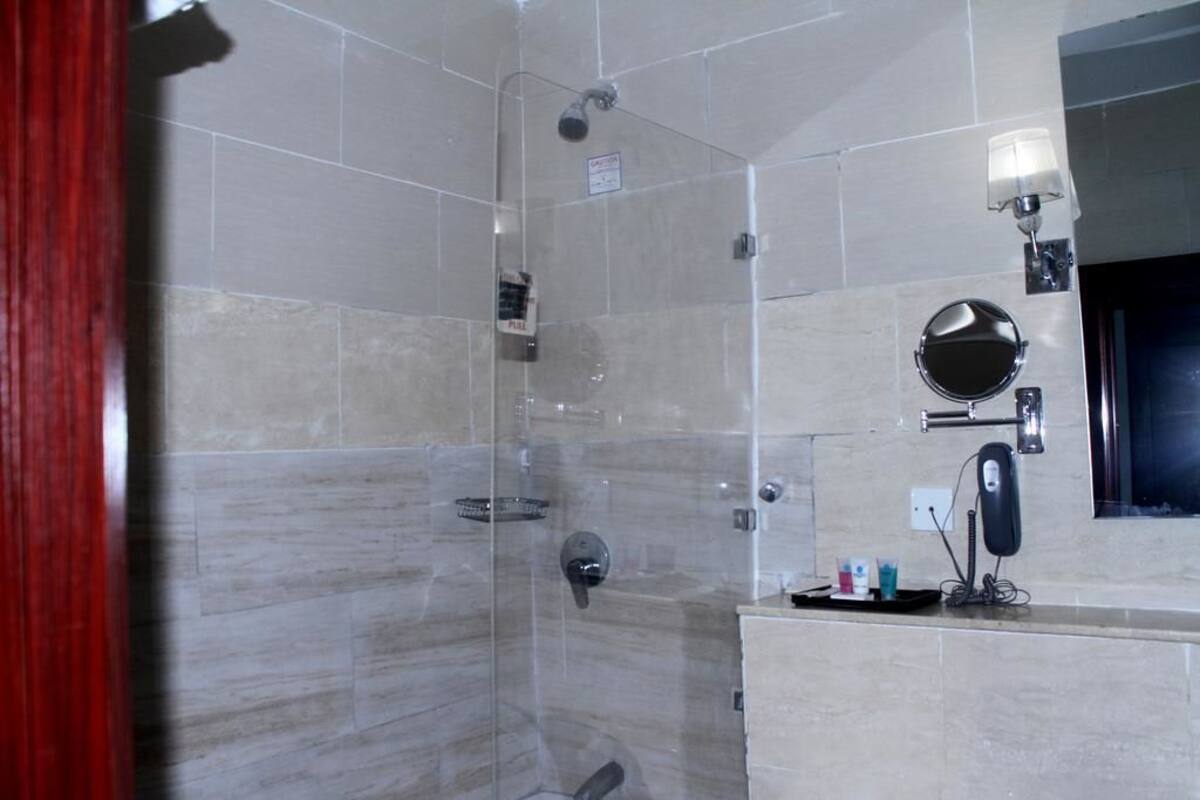 Een moderne badkamer met een douche met glazen wand, een wastafel met spiegel en een handdoekhouder.