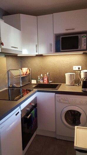 A compact kitchen with white cabinets, a microwave, a dishwasher, and a washing machine. - Le lavandou, lovely small air-conditioned mazet 3 minutes from the beach and shops (Le Lavandou)