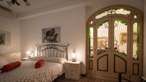 A bedroom with a bed, nightstands, a dresser, and a decorative door with stained glass. - Beautiful apartment 100 meters from the center of Rome Vatican (Roma)