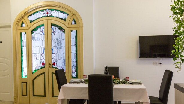 A dining area with a table set for two, a TV mounted on the wall, and a stained glass door. - Beautiful apartment 100 meters from the center of Rome Vatican (Roma)
