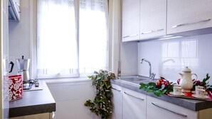 A modern kitchen with white cabinets, a sink, and a window with curtains. - Beautiful apartment 100 meters from the center of Rome Vatican (Roma)