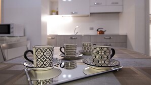 Moderni keittiö, jossa on valkoiset kaapit, mikroaaltouuni ja vedenkeitin työtasolla.