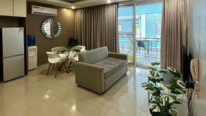 Una sala moderna con un sofá, una mesa de comedor con sillas, una planta en maceta y vistas al exterior.