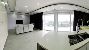 Una cocina moderna con una isla central, un comedor con vistas y un espacio de sala de estar con televisión y asientos.