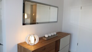 Un aparador de madera con un espejo encima, una pared blanca y una puerta a la derecha.