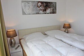 Une chambre d’hôtel avec un lit, deux lampes de chevet, une télécommande et un tableau au mur.