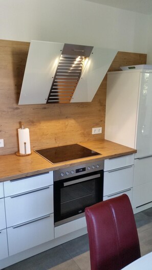 Une cuisine moderne dotée d’un plan de travail en bois, d’appareils électroménagers en acier inoxydable et d’un four encastré.