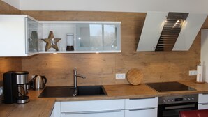 Una cocina moderna con encimera de madera, pileta integrada, cafetera y estufa.