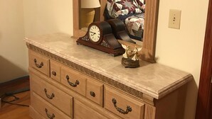 A wooden dresser with a mirror, a clock, and a patterned cloth.