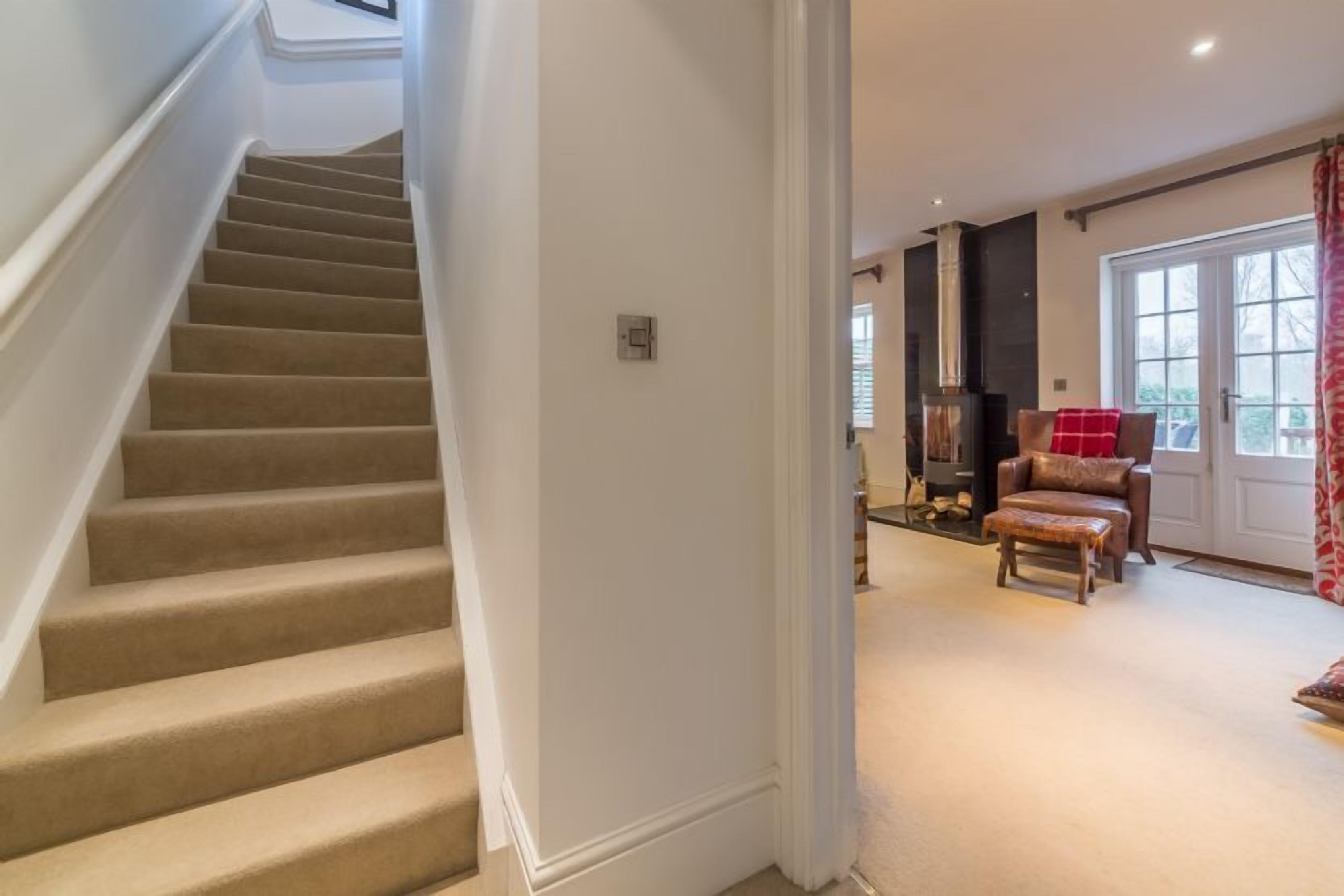 A staircase leading to a living area with a fireplace, a sofa, and a window with curtains.