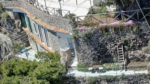 Un hotel sul lungomare con facciata in pietra, posti a sedere all'aperto e vista mare.
