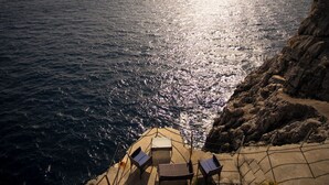 Una terrazza vista mare con tavolo e sedie.