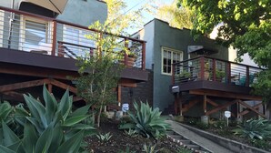 Ein Wohngebäude mit Balkon, Treppe und einem Garten mit unterschiedlichen Pflanzen.