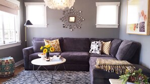 Ein modernes Wohnzimmer mit einem dunkelgrauen Sofa, einem runden Couchtisch und einem gemusterten Teppich.