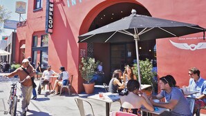 Ein Außenbereich mit Tischen und Sonnenschirmen vor einem Café namens 'Intelligentsia'.