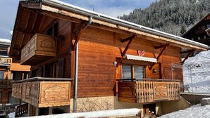 Una baita in legno con balconi, una recinzione in legno e paesaggi innevati.