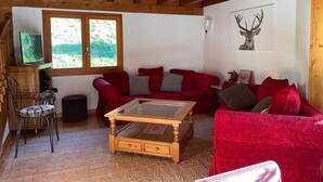 Un accogliente soggiorno con un divano rosso, un tavolino da caffè in vetro e un soffitto in legno.