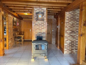 A cozy room with a fireplace, wooden walls, and a tiled floor.