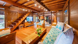 A spacious living area with a wooden staircase, a sofa set, and a television.