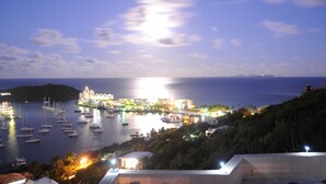 A coastal town at night with illuminated buildings, a marina with boats, and a view of the sea. - SERENDIPITY ocean views Villa Serenity & Villa Serenade A Unique Island Escape.  (Upper Prince's Quarter)