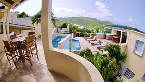 A pool area with lounge chairs and a table, surrounded by potted plants and a view of green hills. - SERENDIPITY ocean views Villa Serenity & Villa Serenade A Unique Island Escape.  (Upper Prince's Quarter)