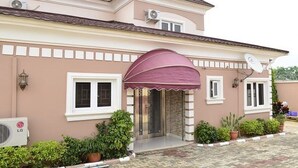 Une maison à deux étages, dotée d’un porche, d’une antenne parabolique et de plantes en pot.