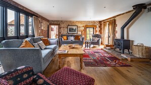 Un salon chaleureux avec une cheminée, un canapé, une table basse et un tapis à motifs.