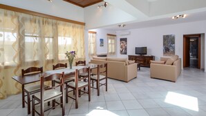 Uma sala de estar ampla com mesa de jantar, sofás e televisão.
