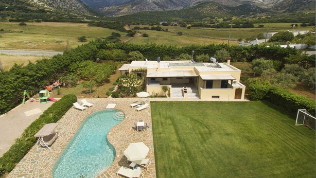 Uma casa moderna com piscina, área de estar externa e vista para montanhas.