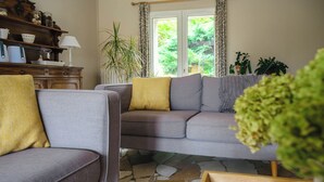 Un salon avec un canapé gris, une table d’appoint en bois et une plante en pot.