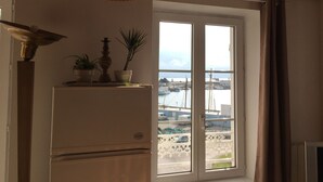 Une cuisine équipée d’un réfrigérateur, d’un luminaire suspendu et d’une fenêtre donnant sur un port de plaisance.