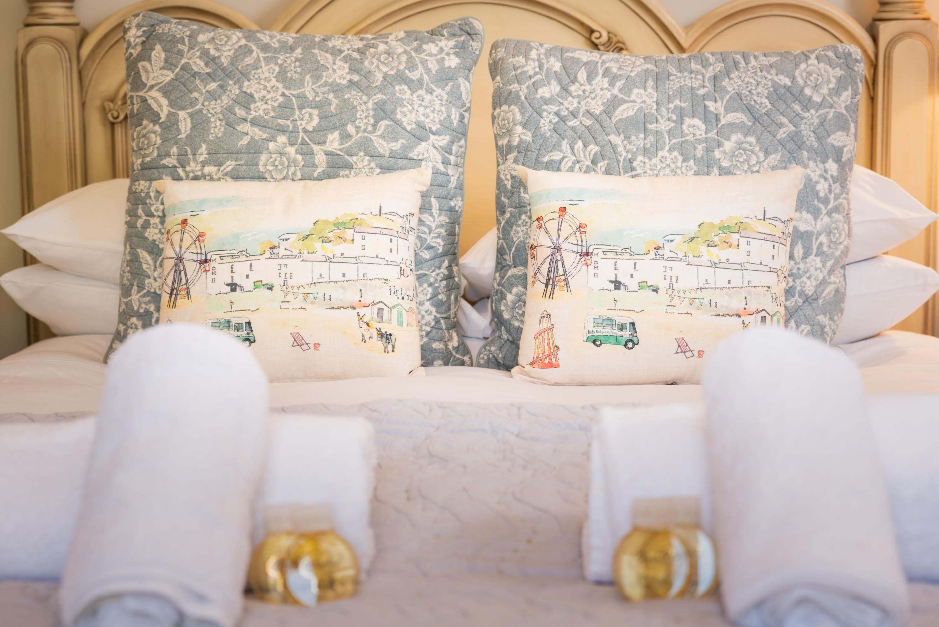 Ein Bett mit zwei Kissen, einer Stadtillustration, einem Blumenmuster am Kopfteil und einem marmorähnlichen Kopfteil.