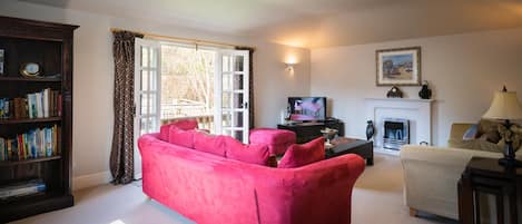 Una sala de estar con un sofá rojo, una estantería, una chimenea y un televisor.