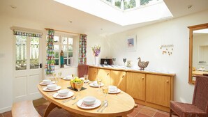 A dining area with a round wooden table set for four, a bench, and a wicker chair.