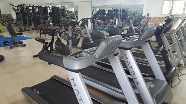 A gym with multiple treadmills, weight machines, and exercise mats. - Nugget Hotel (Abuja)