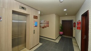 A hallway with an elevator, a fire extinguisher, and a door. - Nugget Hotel (Abuja)