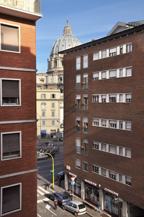 A street view with a prominent red brick building, a dome structure in the background, and a storefront with a sign.