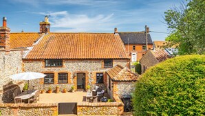 A stone building with a tiled roof, outdoor seating, and a hedge. - Angel Cottage, Great Walsingham, Norfolk (Walsingham)
