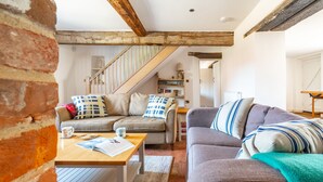 A cozy living room with a staircase, a coffee table, and a sofa. - Angel Cottage, Great Walsingham, Norfolk (Walsingham)