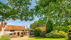 A stone house with a tiled roof, a gravel driveway, and a well-maintained lawn. - Angel Cottage, Great Walsingham, Norfolk (Walsingham)