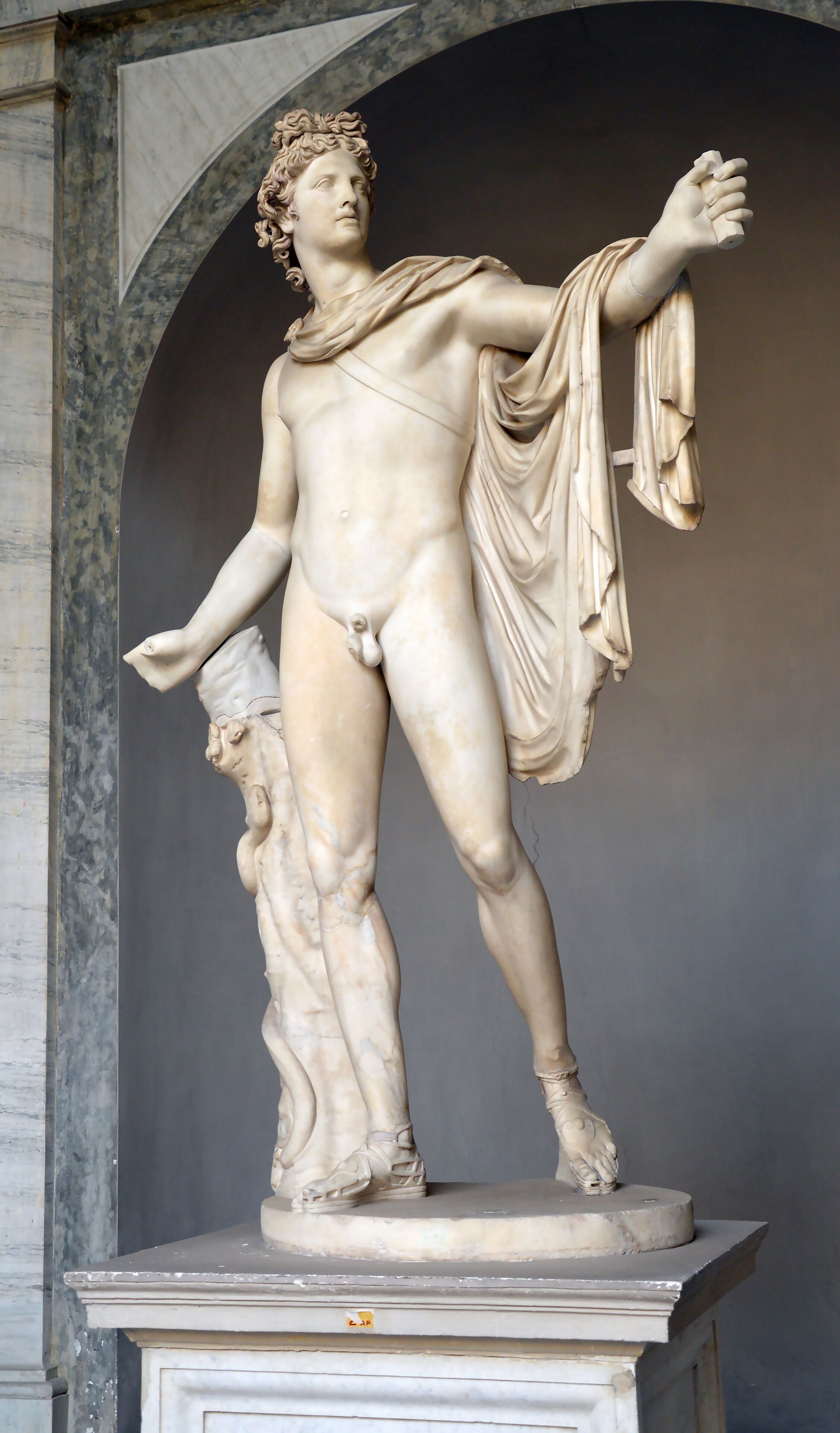 A marble statue of a classical figure with a draped garment, standing on a pedestal.