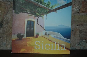 Ein Buchcover zeigt eine Küstenlandschaft, eine Tür und einen Blumentopf.
