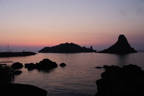 Eine Küstenlandschaft mit einer markanten Felsformation und einer kleineren Insel in der Ferne.