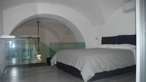 Una camera da letto con un letto, una parete divisoria in vetro e una scala che conduce a un piano superiore.