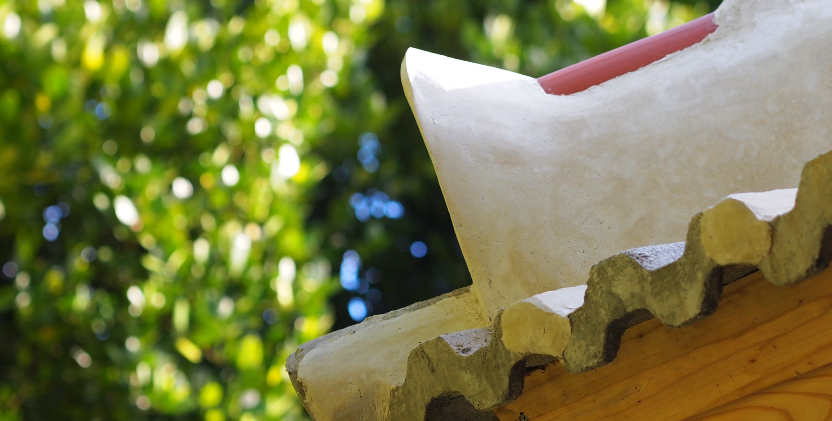 A close-up of a wooden structure with a rough, unfinished edge and a red object on top.