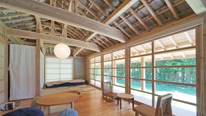 Una habitación amplia con techo alto, ventanas grandes y suelo de madera.