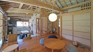 Una habitación amplia con techo alto, vigas de madera, una gran mesa redonda y una puerta corredera tradicional japonesa.