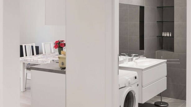 A modern bathroom with a large mirror, white vanity, and a shower area. - Appartamento con due camere a 1 km da Piazza Erbe (Verona)