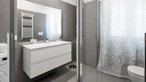 A modern bathroom with a white vanity, a glass shower enclosure, and a patterned shower curtain. - Appartamento con due camere a 1 km da Piazza Erbe (Verona)