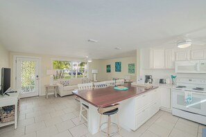 A kitchen with a central island, white cabinetry, a microwave, and a stove. - 2BR Oasis • Dog Friendly • 5 min to Manasota Beach (Englewood)